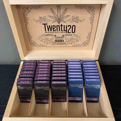 A Twenty20 Mendocino Wooden Display Case labeled "Twenty20 Mendocino Seeds" contains multiple packets of seeds organized in rows. Each packet is designed with a striking purple and black color scheme.